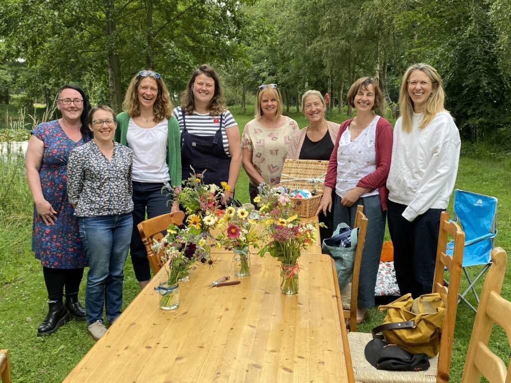 group of people standing behind a table full of flowers 