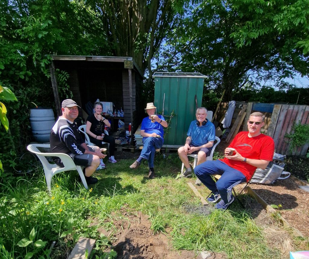 A group of people sitting at an allotment 