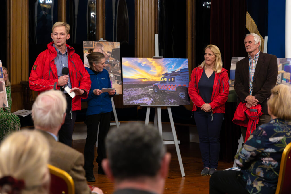 Scarborough Mountain Rescue explaining the work they do in front of a photo of their landrover