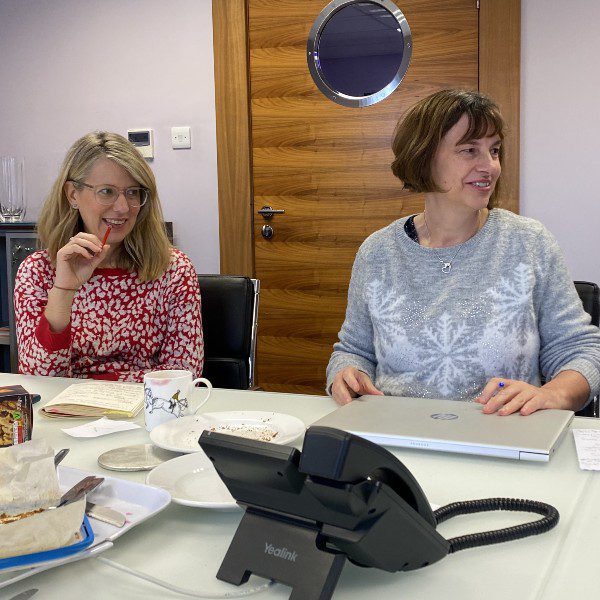 Two people sitting at a desk with a phone in the foreground