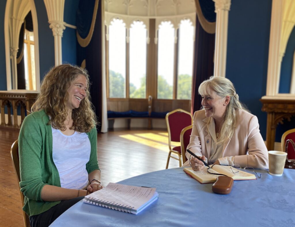 Two women smiling at each other at a desk: Celica McKeon and Dr. Ruth Smith